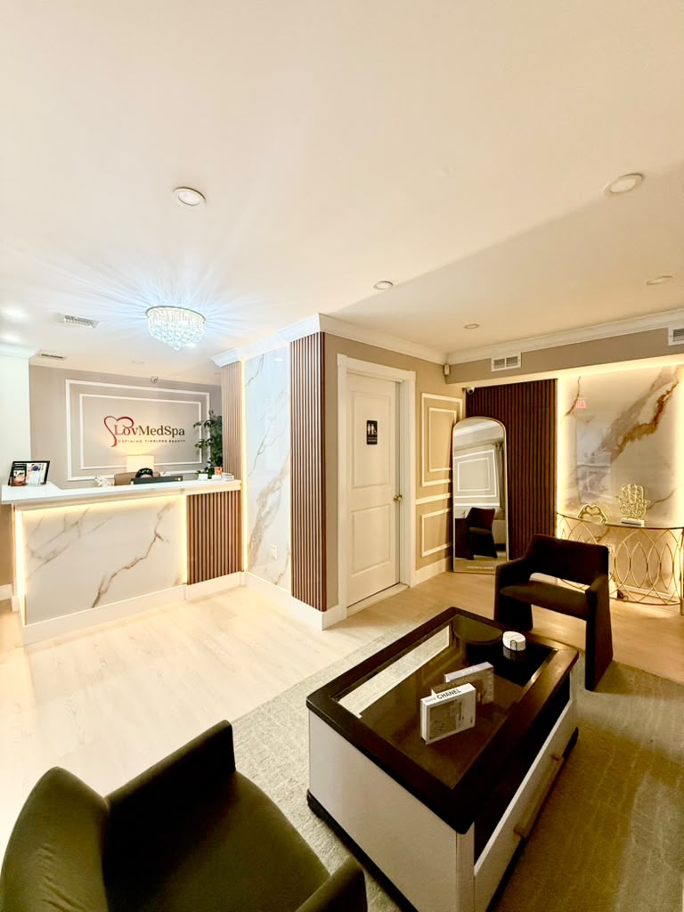 Reception and waiting lounge at LovMedSpa Staten Island, with marble front desk, crystal chandelier, and velvet seating